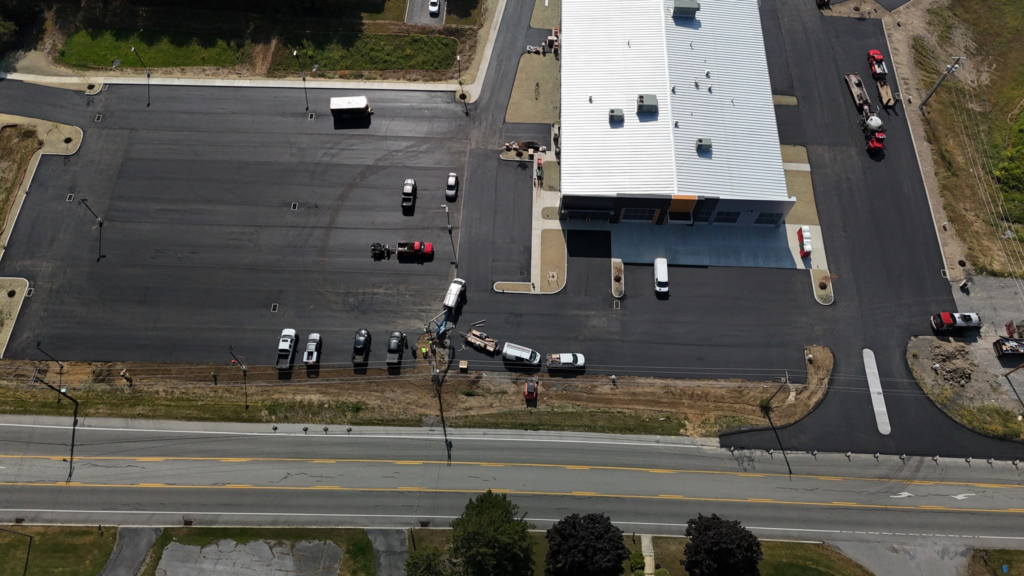 Aerial view of a newly built commercial building in Blair County, Pennsylvania, with its parking lot paved and site lighting poles being set.